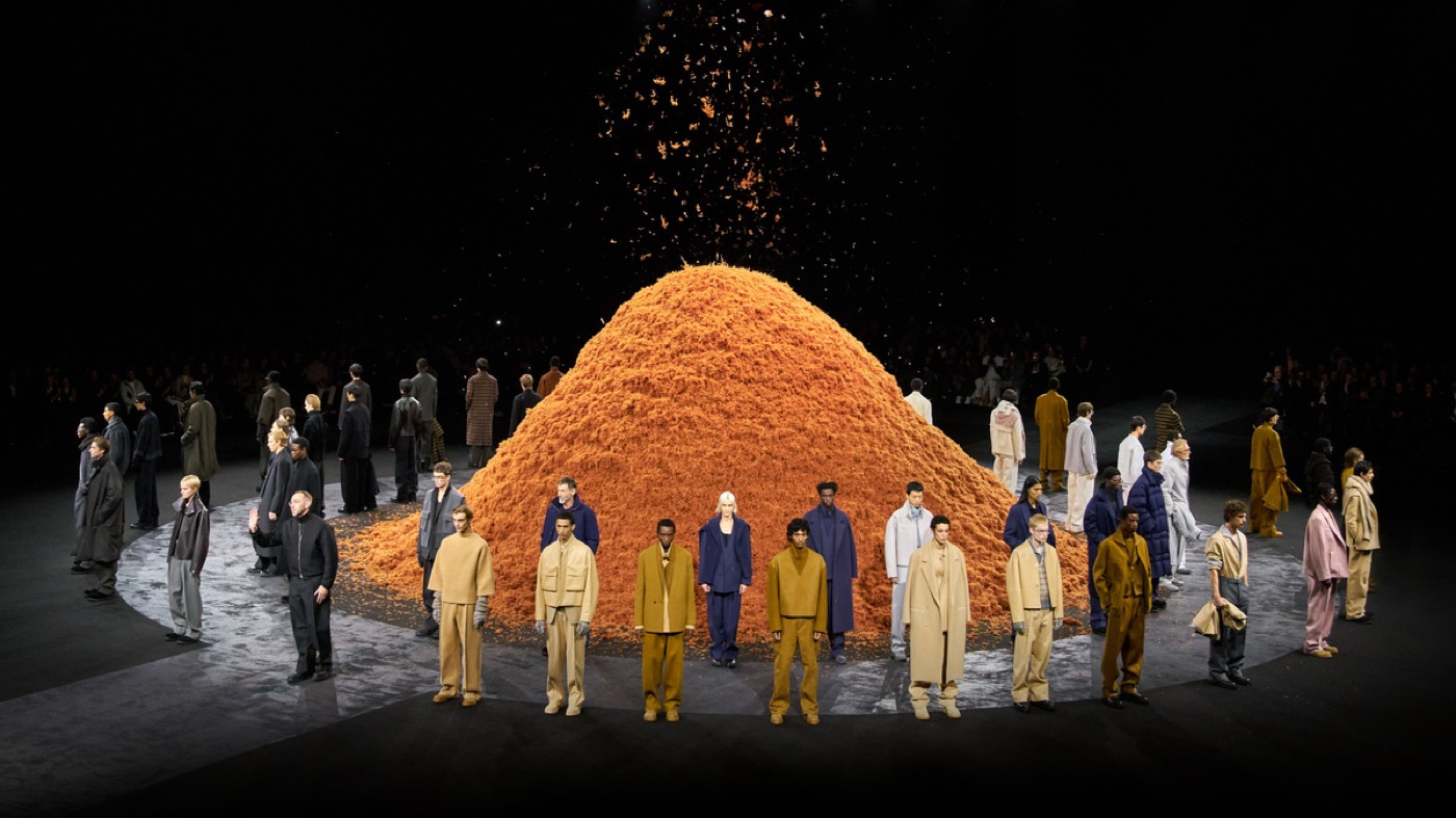 ZEGNA FW24 runway: models encircle a vast mound of raw cashmere in a dark hall
